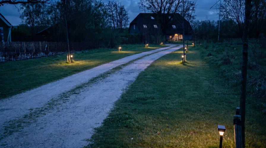 Padverlichting langs een lange oprit wijst de weg naar de woning en verhoogt veiligheid in het donker