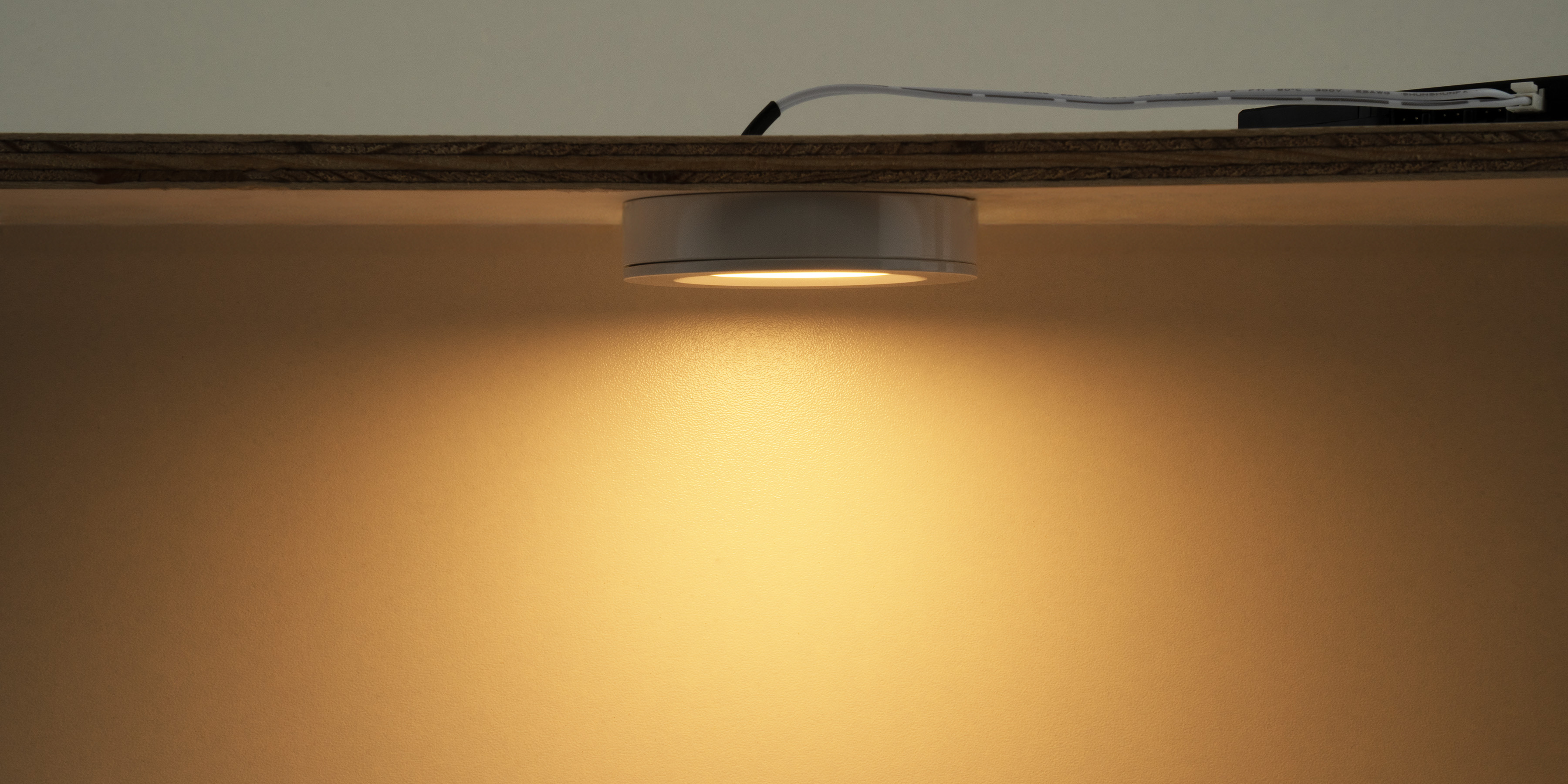 LED-opbouwspot onder plank gemonteerd die warm wit licht naar beneden schijnt voor gerichte verlichting