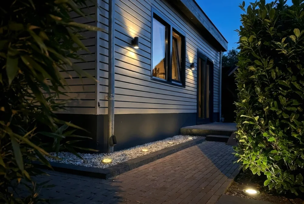 Buiten wandverlichting langs de gevel en het tuinpad geeft warm licht en maakt de entree overzichtelijk