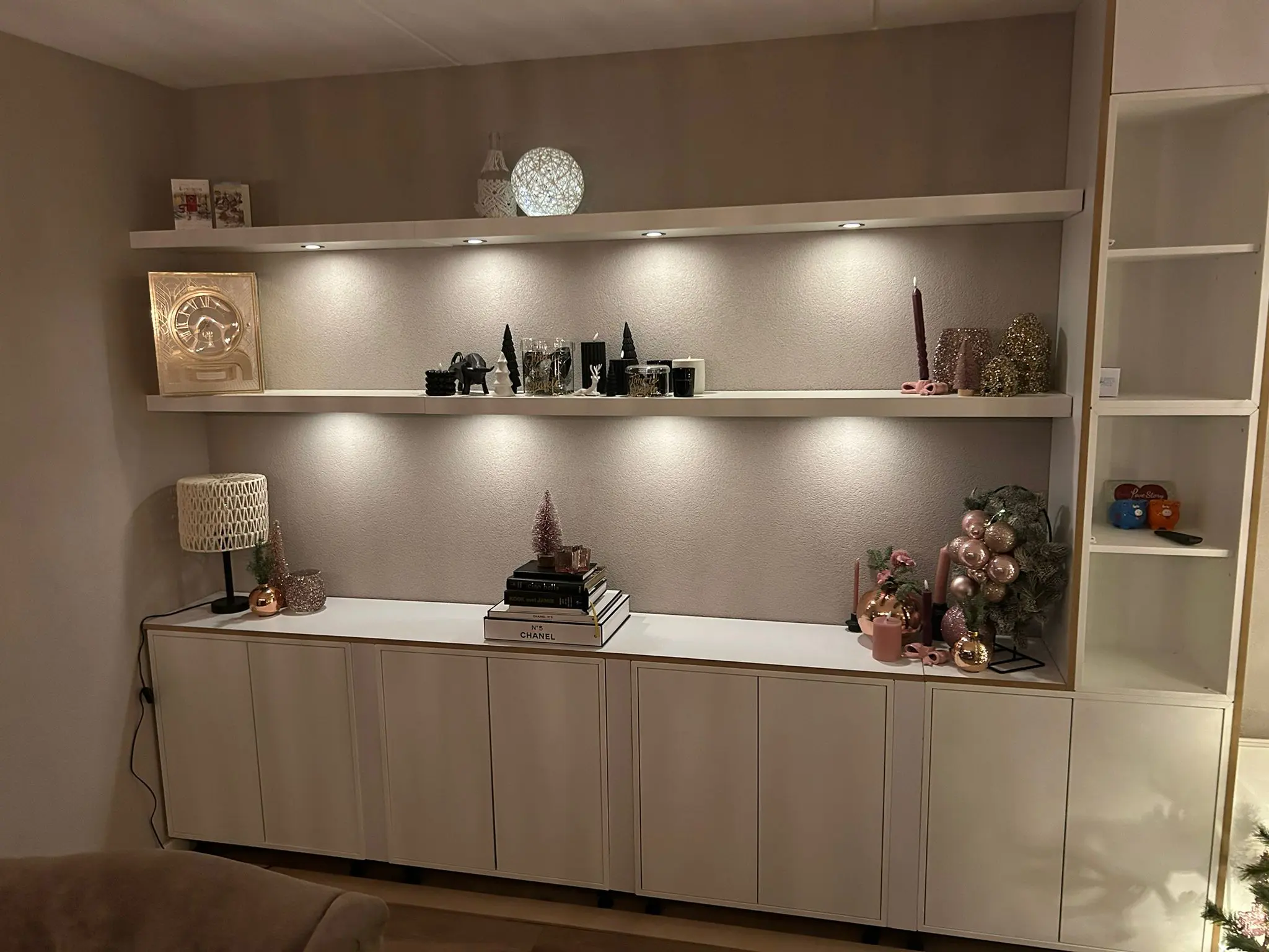 Wandmeubel met lage LED inbouwspots onder de plank die decoratie subtiel en warm uitlichten